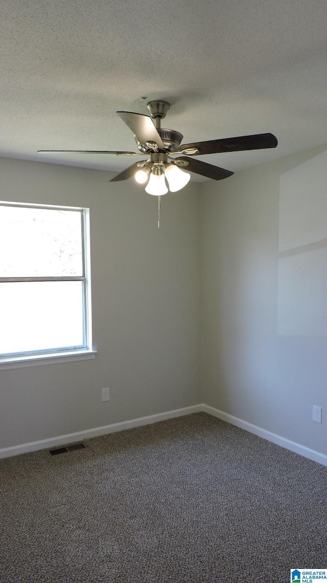 carpeted spare room with baseboards, visible vents, ceiling fan, and a textured ceiling