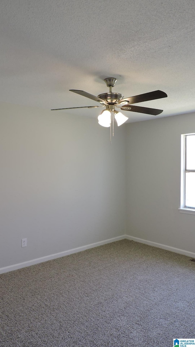 carpeted empty room with a ceiling fan, baseboards, and a textured ceiling