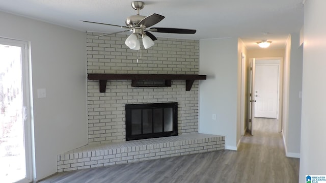 unfurnished living room with a ceiling fan, baseboards, a fireplace, and wood finished floors