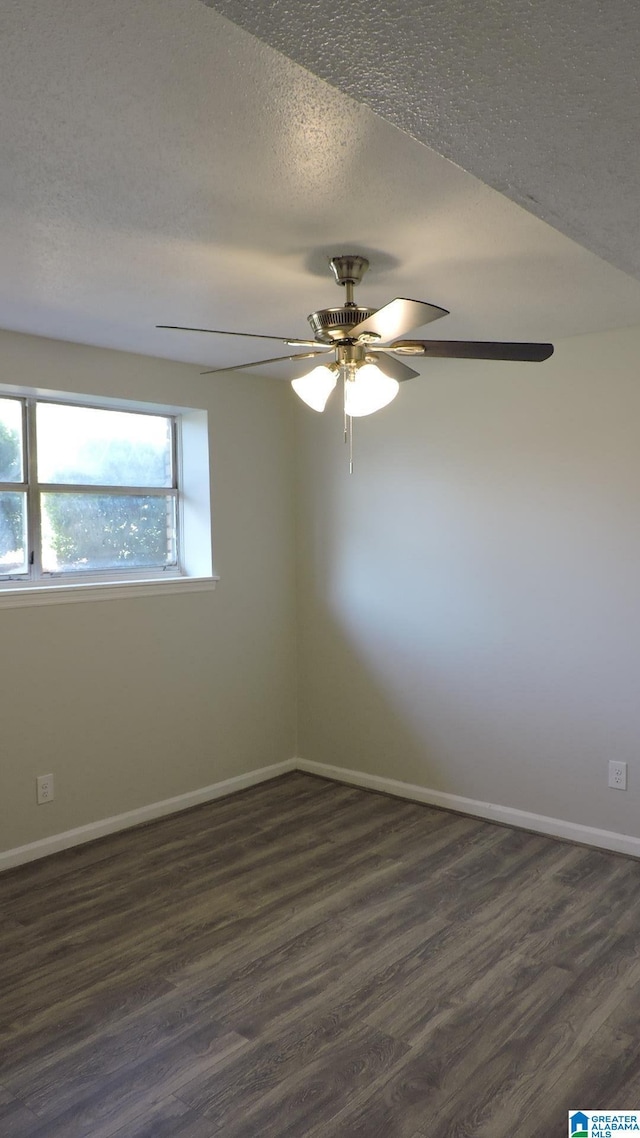empty room with dark wood-type flooring, a textured ceiling, baseboards, and ceiling fan