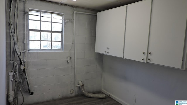 laundry area with concrete block wall, wood finished floors, and electric dryer hookup