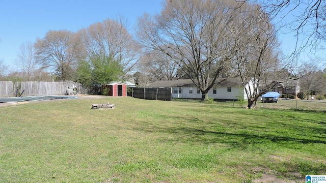view of yard featuring a fenced backyard, an outdoor fire pit, a shed, and an outbuilding