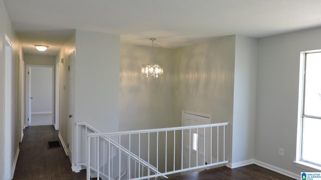 hallway featuring an upstairs landing, visible vents, a notable chandelier, and dark wood finished floors