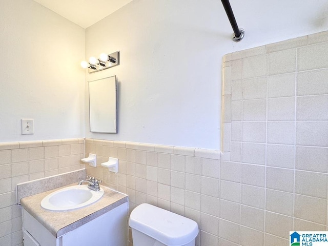 7709 7th Ave S, Birmingham, AL 35206 - bathroom featuring tile walls, toilet, vanity, and wainscoting