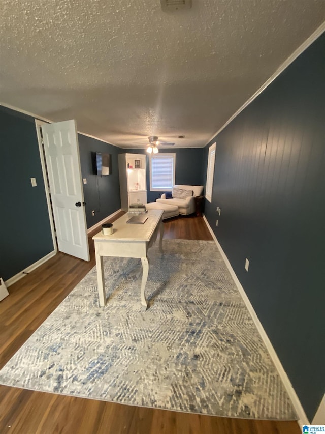 playroom featuring dark wood-style floors, crown molding, baseboards, and a textured ceiling