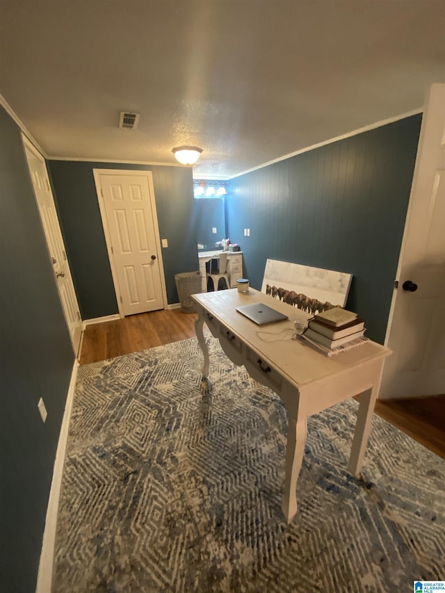 home office featuring baseboards, visible vents, wood finished floors, and crown molding