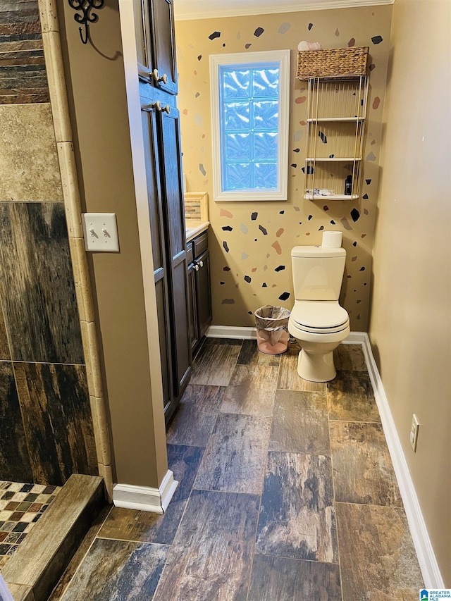 bathroom with baseboards, toilet, tiled shower, and vanity