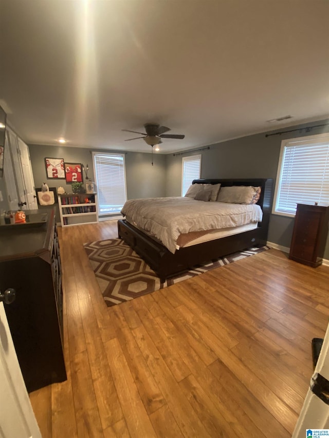 bedroom with wood-type flooring, baseboards, ceiling fan, and visible vents