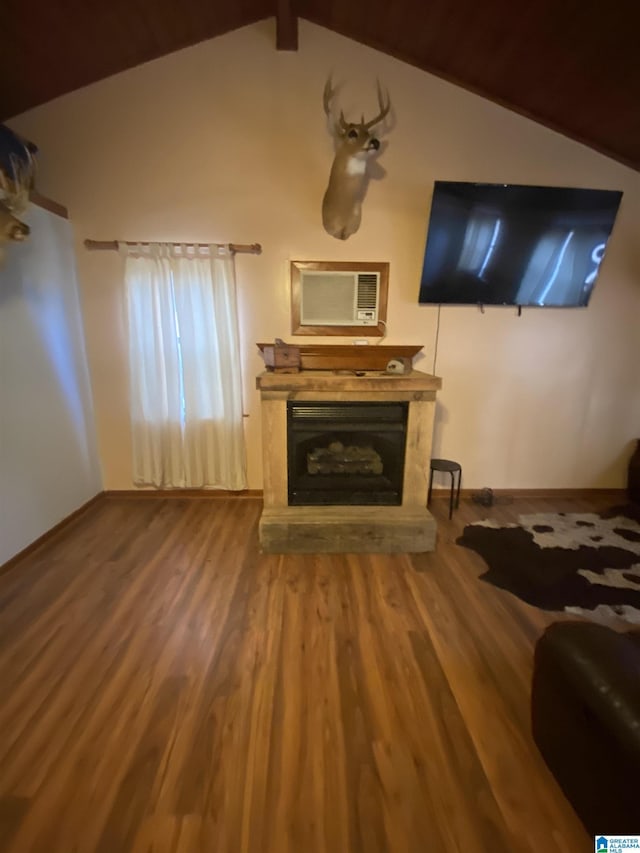 unfurnished living room featuring vaulted ceiling with beams, wood finished floors, a fireplace with raised hearth, and baseboards