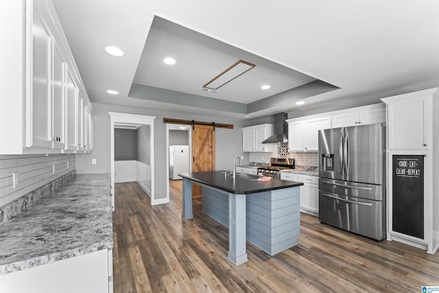 kitchen with white cabinets, wall chimney range hood, stainless steel appliances, and a raised ceiling