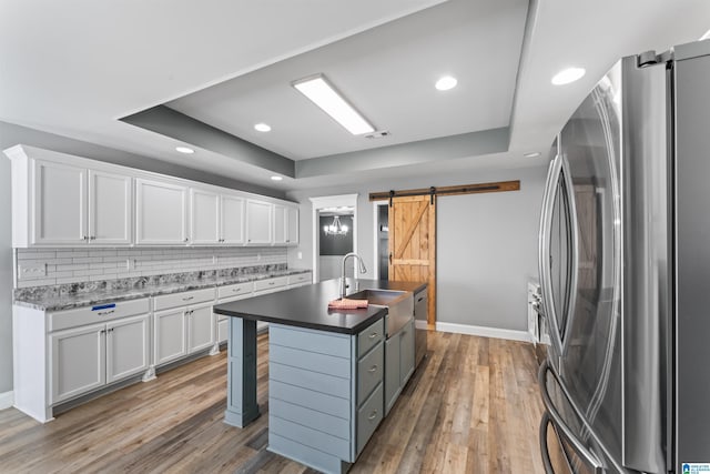 kitchen featuring a barn door, white cabinets, a raised ceiling, and freestanding refrigerator