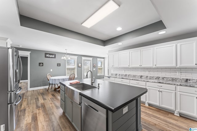 kitchen with white cabinetry, a raised ceiling, a sink, and stainless steel appliances