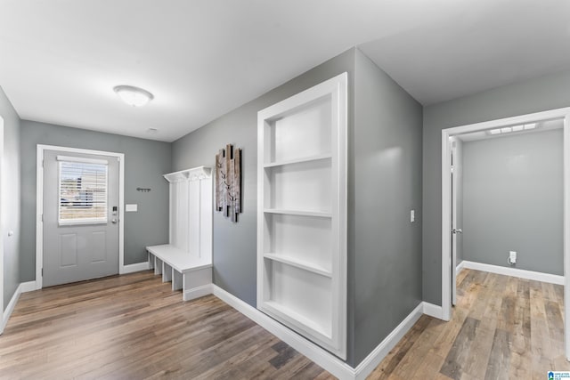 mudroom featuring baseboards, wood finished floors, and built in shelves