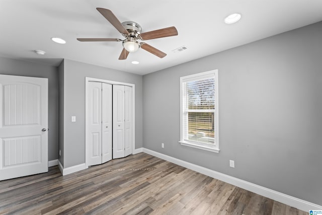 unfurnished bedroom with baseboards, visible vents, a closet, and wood finished floors