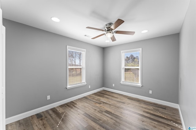 unfurnished room featuring baseboards, wood finished floors, ceiling fan, and a healthy amount of sunlight