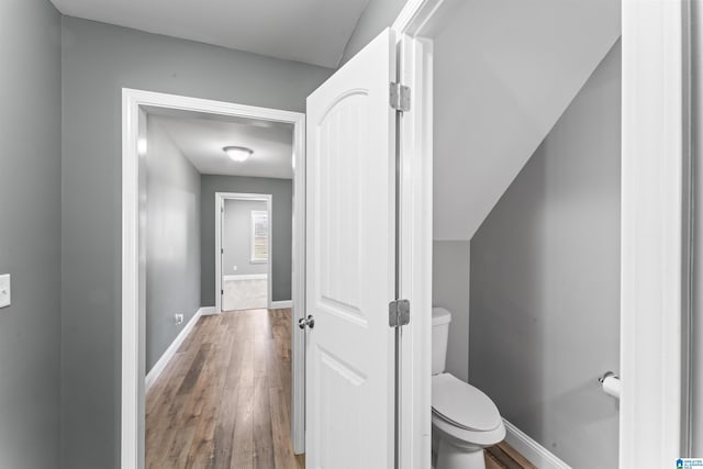 bathroom with baseboards, wood finished floors, and toilet