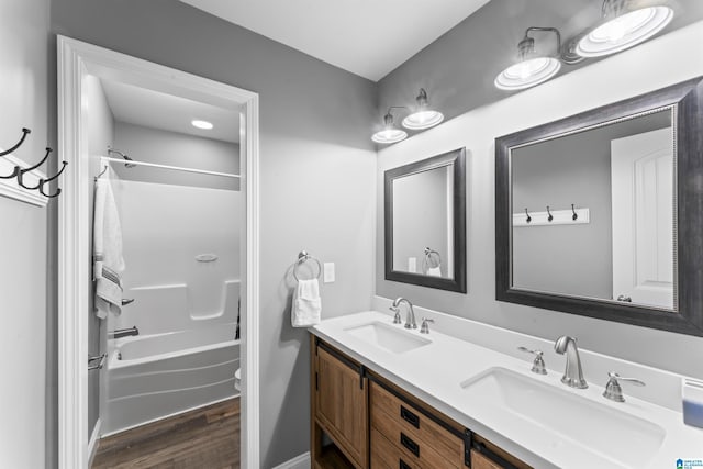 full bath with double vanity, wood finished floors, a sink, and bathing tub / shower combination