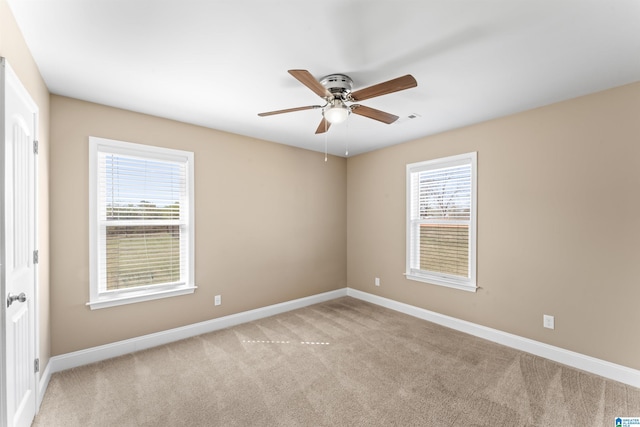 unfurnished room with a wealth of natural light, baseboards, light colored carpet, and ceiling fan