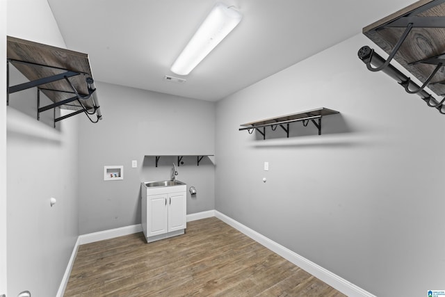 laundry area featuring washer hookup, wood finished floors, a sink, electric dryer hookup, and cabinet space