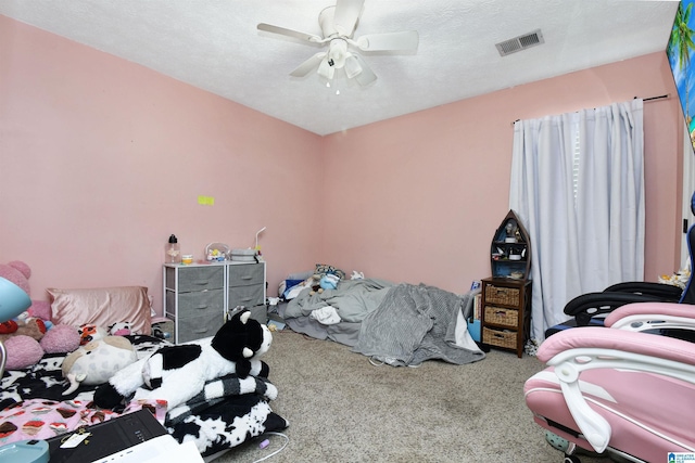 carpeted bedroom featuring a textured ceiling, ceiling fan, and visible vents