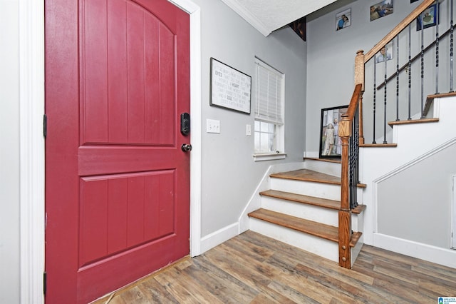 foyer entrance with baseboards, a textured ceiling, wood finished floors, and stairway