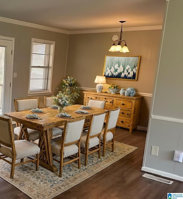 dining space featuring crown molding, dark wood-style floors, baseboards, visible vents, and an inviting chandelier