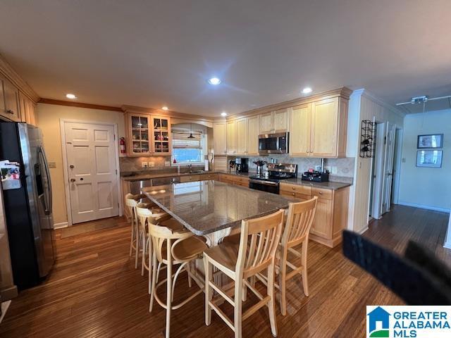 881 Ridgeway Cir, Talladega, AL 35160 - kitchen featuring a breakfast bar area, dark wood-style flooring, ornamental molding, stainless steel appliances, and a kitchen island