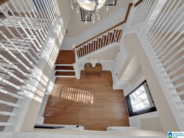 2326 Freestone Ridge Cv, Hoover, AL 35226 - stairs featuring a towering ceiling, wood finished floors, a chandelier, and a decorative wall