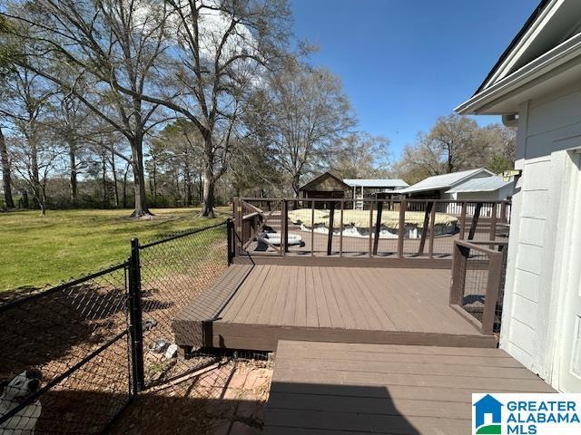 wooden terrace featuring fence and a yard