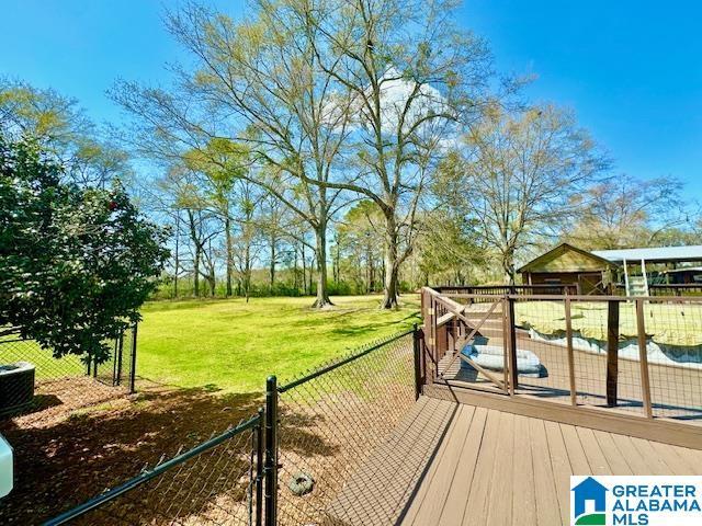 wooden deck with fence, central AC unit, and a yard