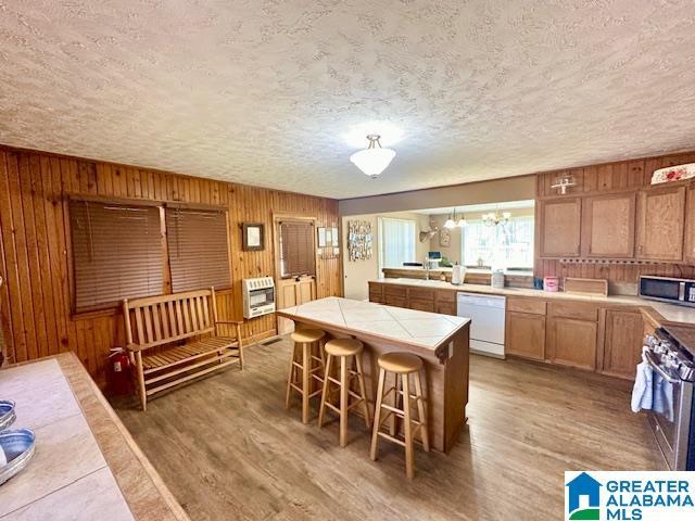 kitchen featuring appliances with stainless steel finishes, heating unit, tile countertops, light wood-style floors, and an inviting chandelier