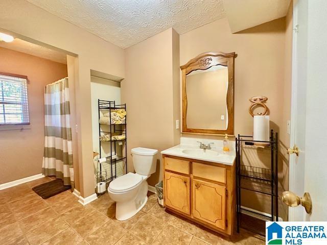bathroom featuring a textured ceiling, baseboards, toilet, curtained shower, and vanity