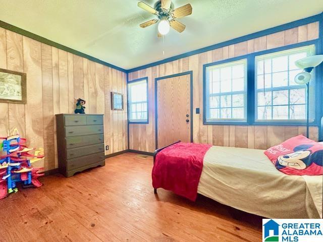 bedroom featuring multiple windows, wood finished floors, and a ceiling fan