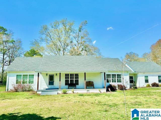 back of property with a lawn and a porch