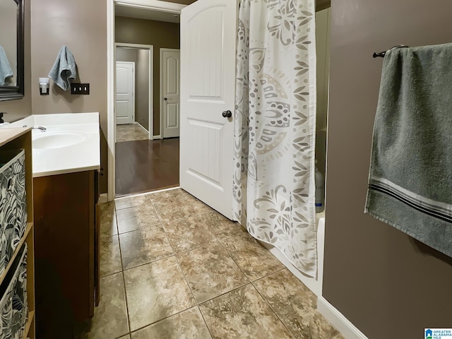 bathroom with shower / bath combo, tile patterned floors, vanity, and baseboards