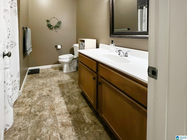 full bath with toilet, vanity, and baseboards