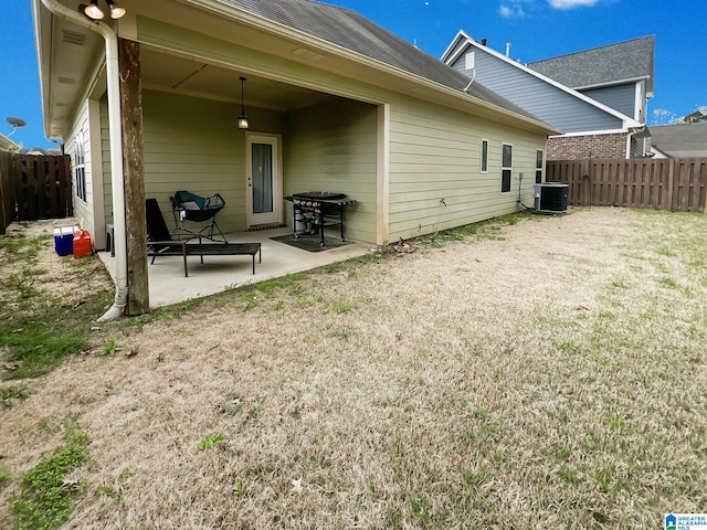 rear view of house featuring a patio, a fenced backyard, cooling unit, and a yard