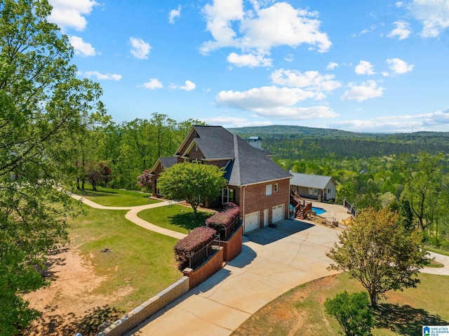 206 Shaw Rd, Pell City, AL 35128 - view of side of home with driveway, an attached garage, a lawn, a shingled roof, and a forest view