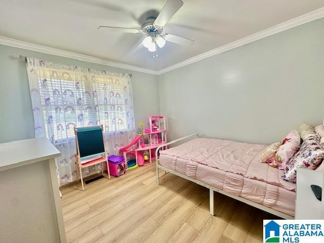 bedroom with wood finished floors, ceiling fan, and ornamental molding