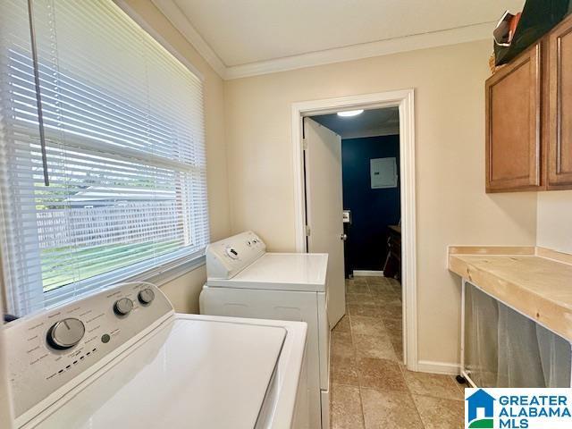 clothes washing area with baseboards, washing machine and dryer, ornamental molding, and cabinet space