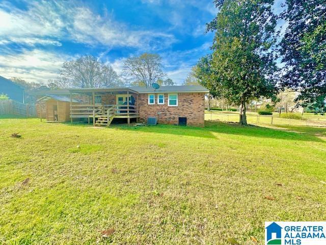 rear view of house featuring a lawn, fence, and central AC