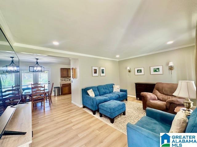 living room featuring baseboards, light wood-type flooring, recessed lighting, and ornamental molding