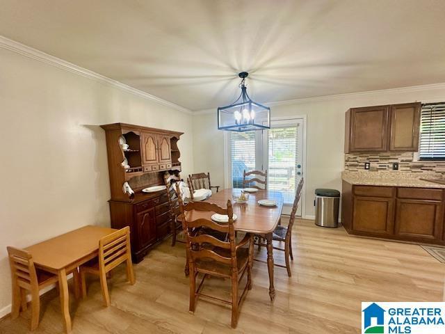 dining space with a notable chandelier, crown molding, and light wood finished floors