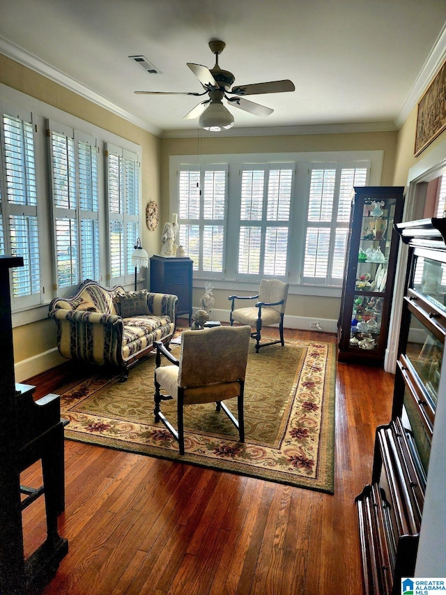 living area with a ceiling fan, wood finished floors, crown molding, and visible vents