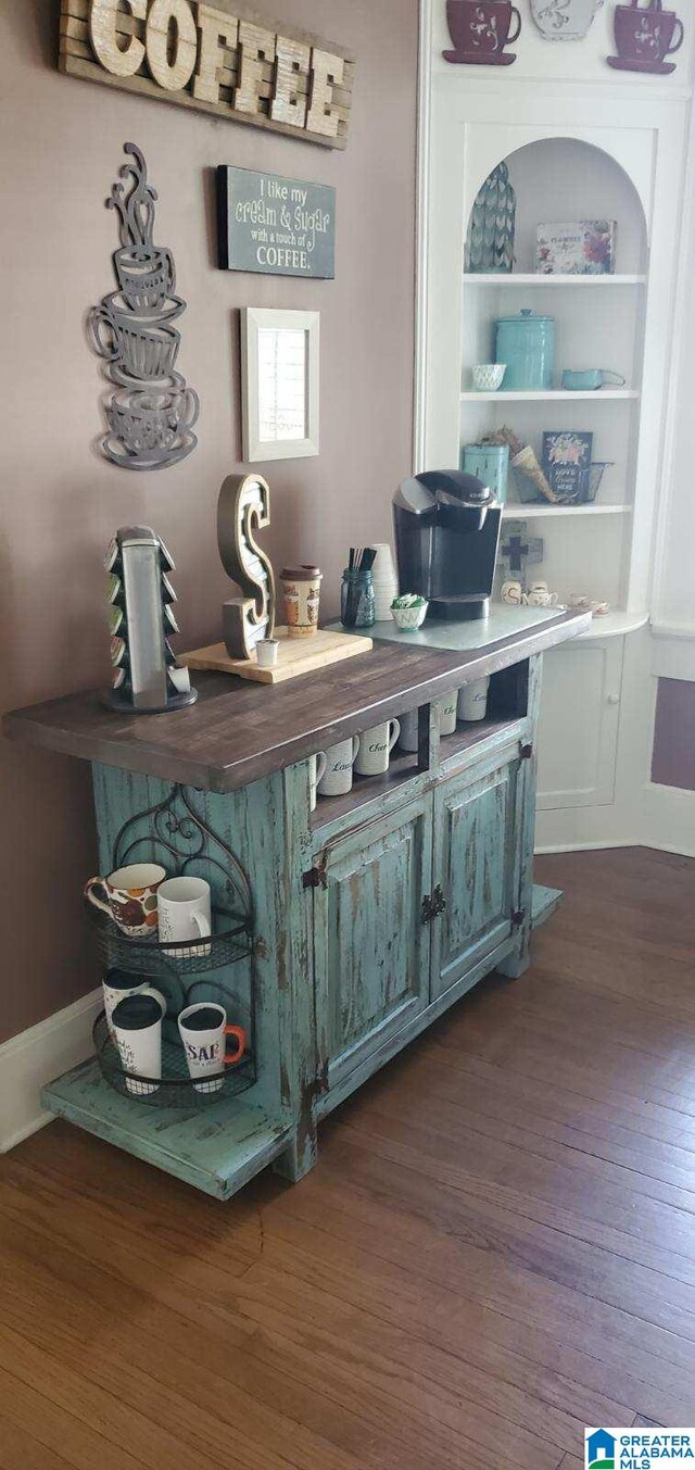bar with dark wood-style floors and built in shelves