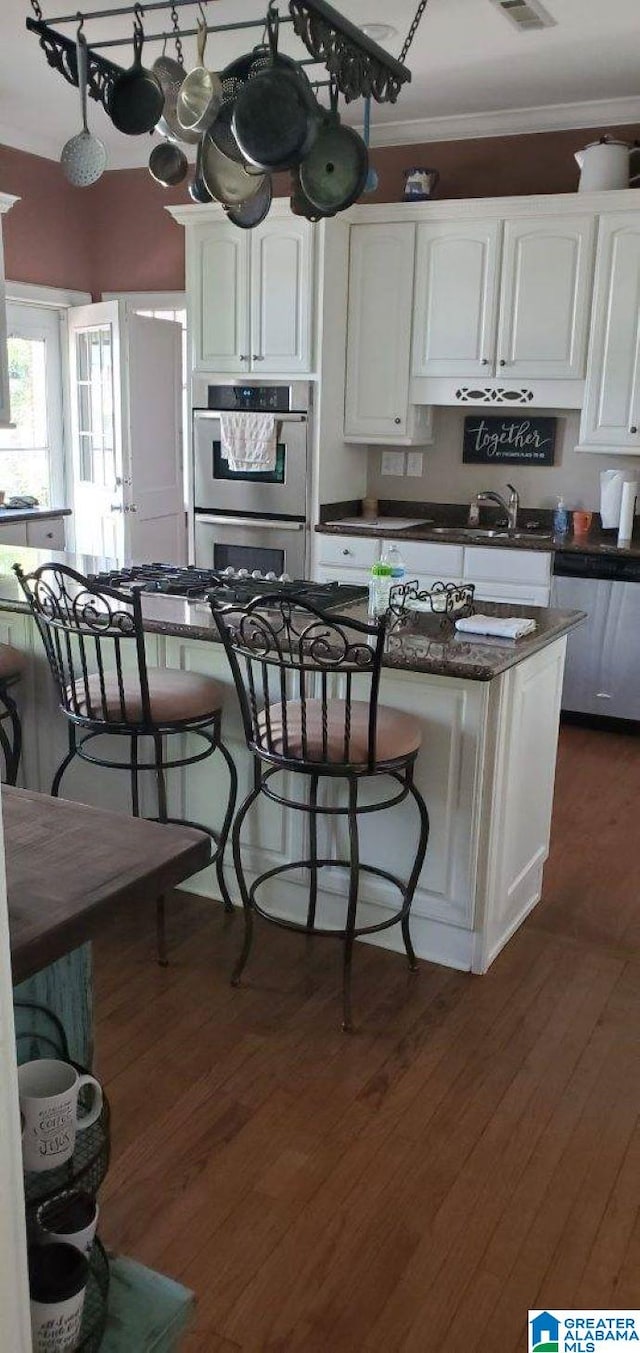 kitchen featuring white cabinetry, ornamental molding, appliances with stainless steel finishes, and dark wood finished floors
