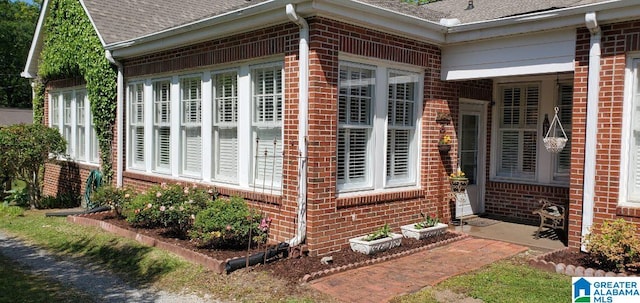 view of side of home featuring brick siding and a shingled roof
