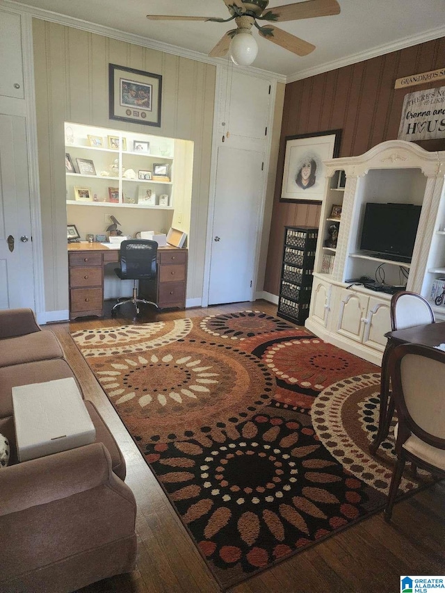 living room with wood finished floors, crown molding, baseboards, and ceiling fan