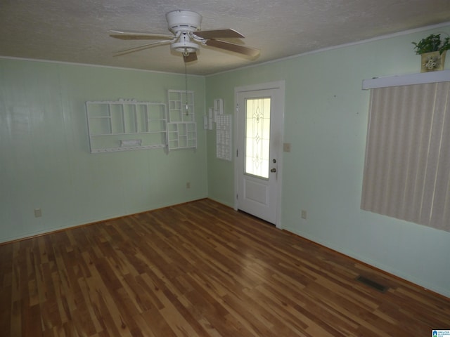 spare room featuring a textured ceiling, visible vents, crown molding, ceiling fan, and wood finished floors