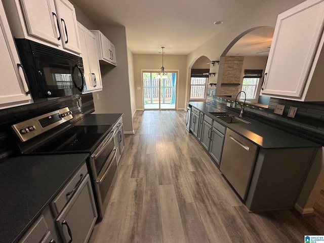 6777 Southern Trace Cir, Leeds, AL 35094 - kitchen with dark countertops, a sink, arched walkways, stainless steel appliances, and backsplash